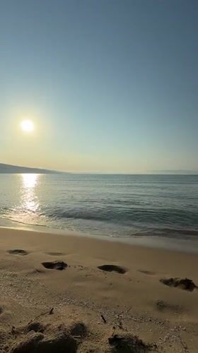 Dawn breaks over Nesebar beach as sunrise illuminates calm waters