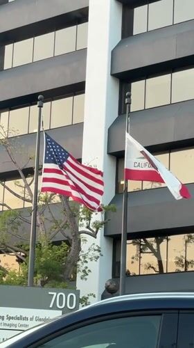 Flags wave outside commercial building in early morning Glendale