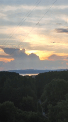 Sunset over wooded landscape with water and apartment building