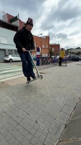 Masked scooter rider performs street tricks in Badalona