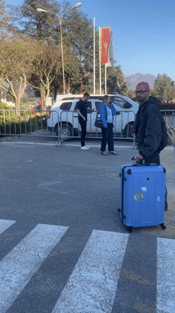 Pink-haired traveler with suitcase crosses street in Montenegro