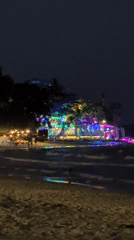 Colorful lights reflect on water at Thailand beach night