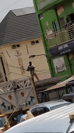 Man with box gestures from truck bed in Nigeria