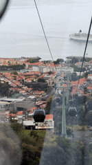 Cable car ride captured over Funchal's red roofs and coastline