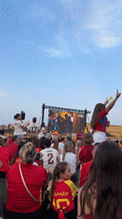 Outdoor crowd in red and yellow watches live sports on big screen