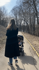 Woman with baby stroller walks through Khimki park