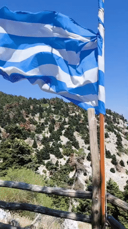 Hilltop views over Acharnes with flags and forested slopes