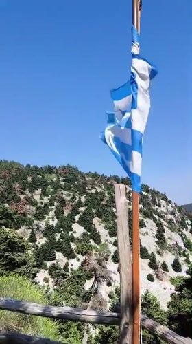 Hilltop views over Acharnes with flags and forested slopes