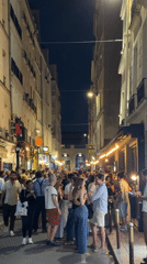 Evening street crowds gather in illuminated Paris neighborhood