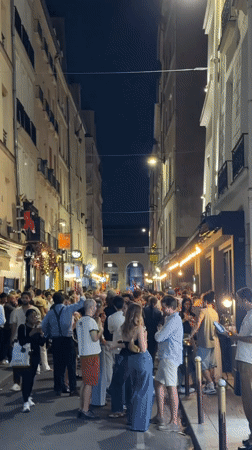 Evening street crowds gather in illuminated Paris neighborhood