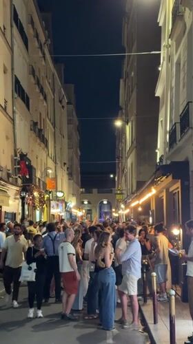 Evening street crowds gather in illuminated Paris neighborhood