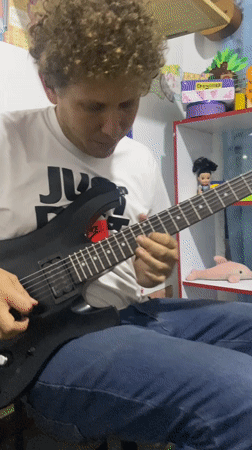 Man plays guitar in classroom decorated with children's artwork