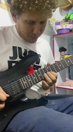 Man plays guitar in classroom decorated with children's artwork