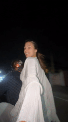 Woman in white rides motorcycle passenger in nighttime Pattaya