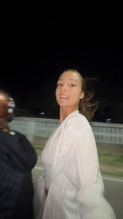 Woman in white rides motorcycle passenger in nighttime Pattaya