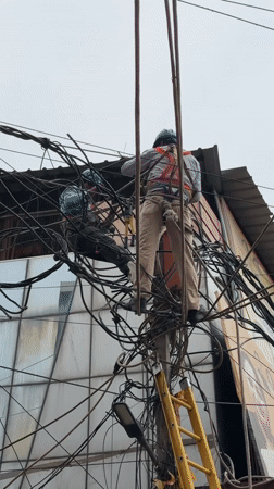 Electrical work on a tangled pole near Mehrauli's historic streets