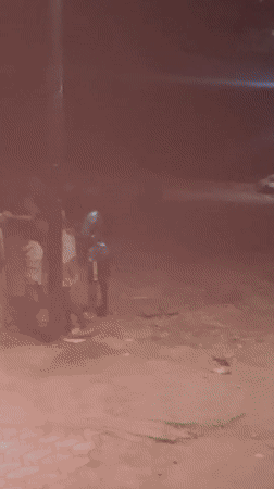 Group gathering near building in Akwanga, one person runs