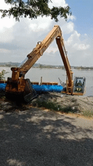 Excavator operates at water's edge in Lhokseumawe, Indonesia