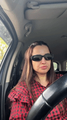 Woman in checkered shirt sits smiling in car