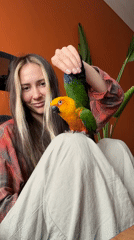 Woman photographed with parrot during indoor interaction session