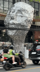 Street life documented around silver head sculpture in Ungasan