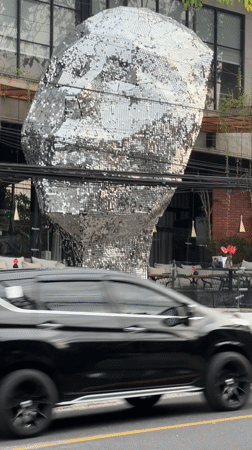 Street life documented around silver head sculpture in Ungasan