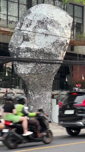Street life documented around silver head sculpture in Ungasan