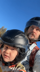 Father, child ride helmeted on motorcycle in Fethiye