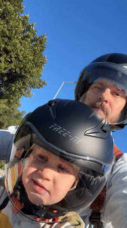 Father, child ride helmeted on motorcycle in Fethiye