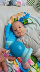 Baby plays with rattle on blanket in Andreyevo