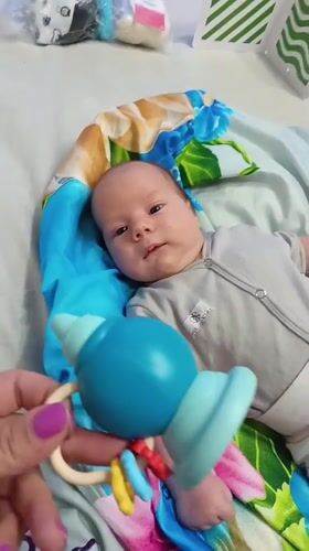 Baby plays with rattle on blanket in Andreyevo