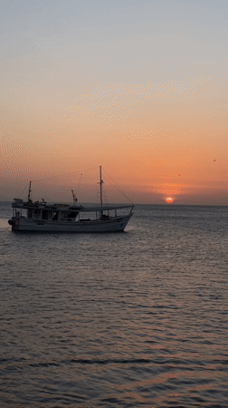 Man takes selfies at Juan Griego harbor during sunset