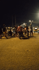 Evening street market bustles with vendors, motorcycles in Bukuru