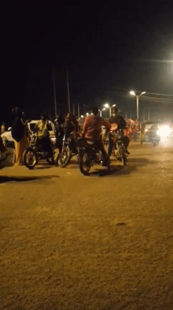 Evening street market bustles with vendors, motorcycles in Bukuru