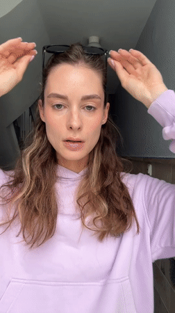 Woman takes selfies while adjusting sunglasses in Kiel building
