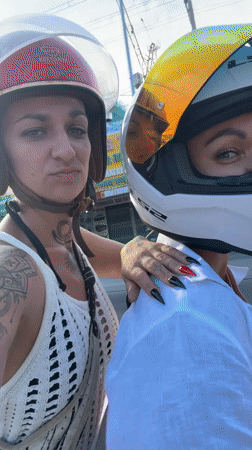 Two women ride motorbike through Vietnamese ward street