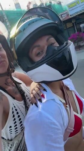 Two women ride motorbike through Vietnamese ward street