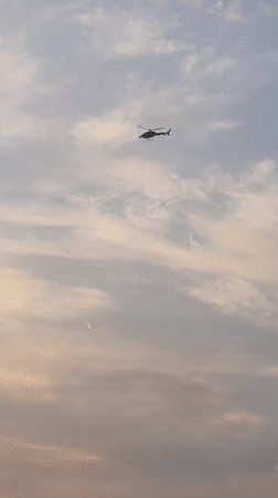 Paris rooftops at dawn on Bastille Day, helicopters overhead