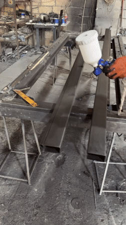 Spray painting a metal object in a Baku workshop