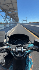 Scooter riders cross Denpasar bridge as plane flies overhead