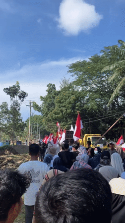 Flag-carrying procession through rural Indonesian streets