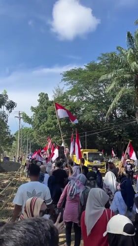 Flag-carrying procession through rural Indonesian streets