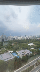 Bangkok skyline viewed from high-rise window overlooking city park