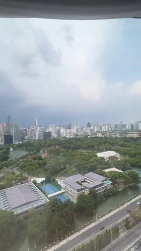 Bangkok skyline viewed from high-rise window overlooking city park