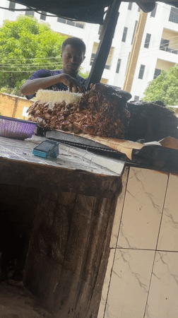 Food vendor prepares cheese-topped meat dish in Nigerian town