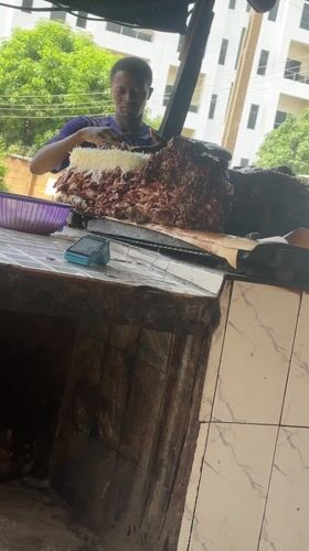 Food vendor prepares cheese-topped meat dish in Nigerian town