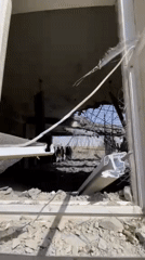 Armed man surveys severely damaged building in Mandisar, Afghanistan