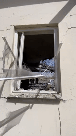 Armed man surveys severely damaged building in Mandisar, Afghanistan