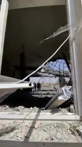 Armed man surveys severely damaged building in Mandisar, Afghanistan