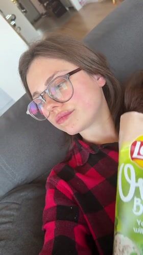 Woman enjoys chips and yogurt snack in Budapest apartment